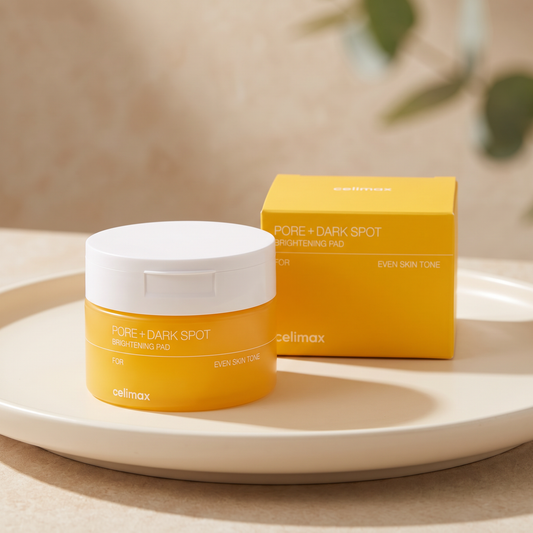Celimax Pore + Dark Spot Brightening Pad jar and box styled on a warm ivory ceramic surface