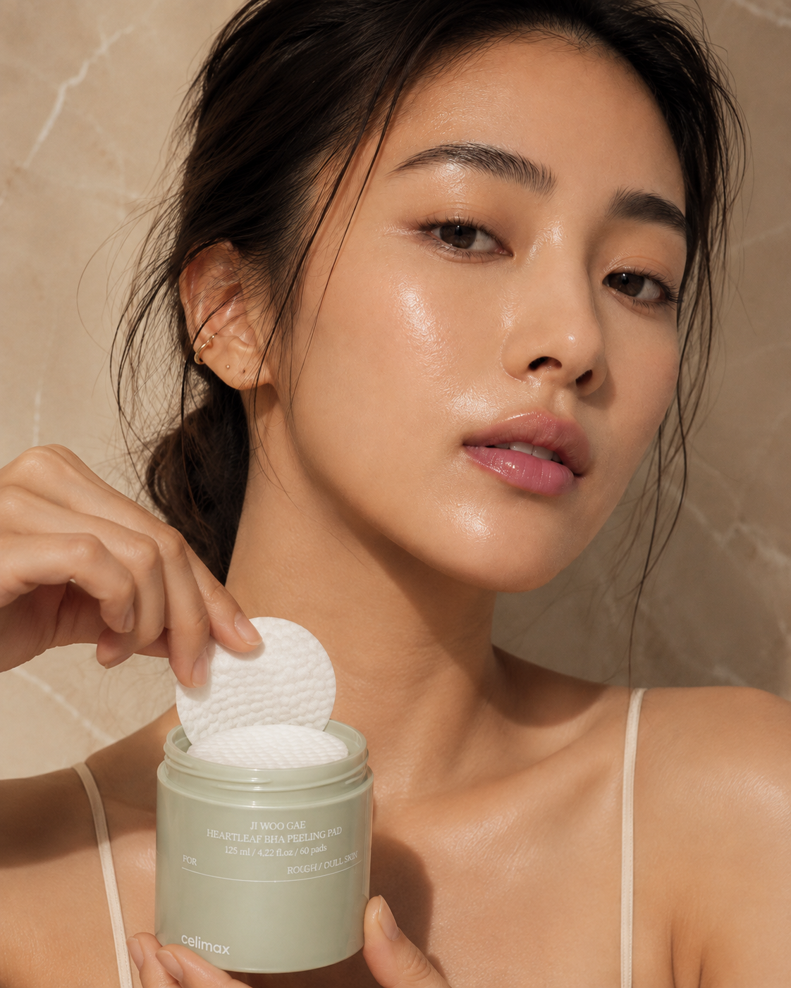 Woman lifting a peeling pad out of the Ji Woo Gae Heartleaf BHA jar