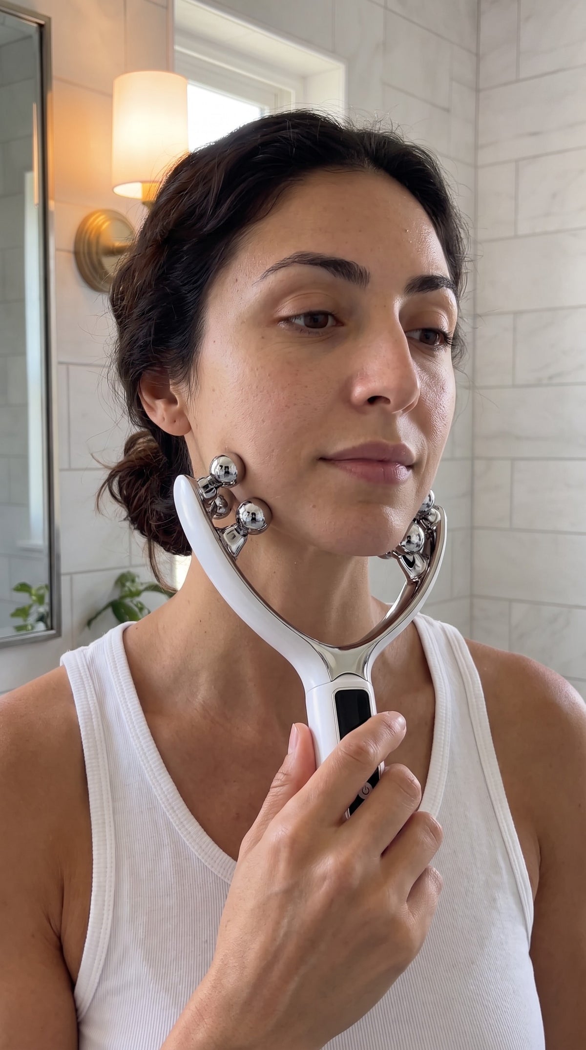 Woman holding the 8-roller facial massager with the chin inside the V and rollers on both sides of the jawline