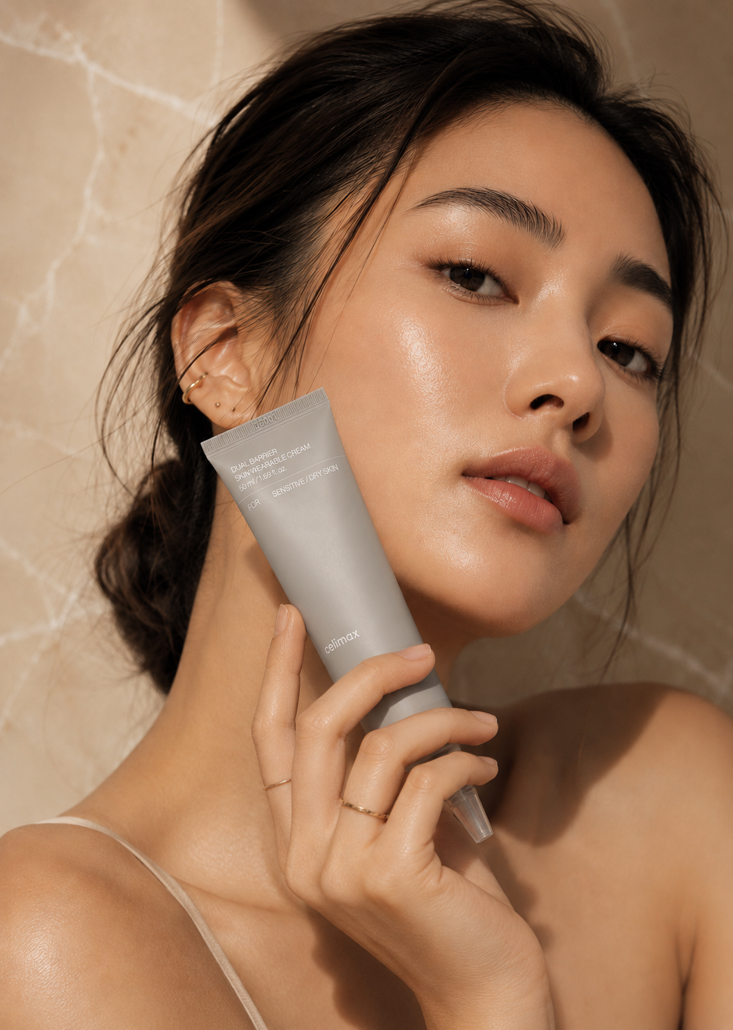 Woman holding Celimax Dual Barrier Cream tube near her face