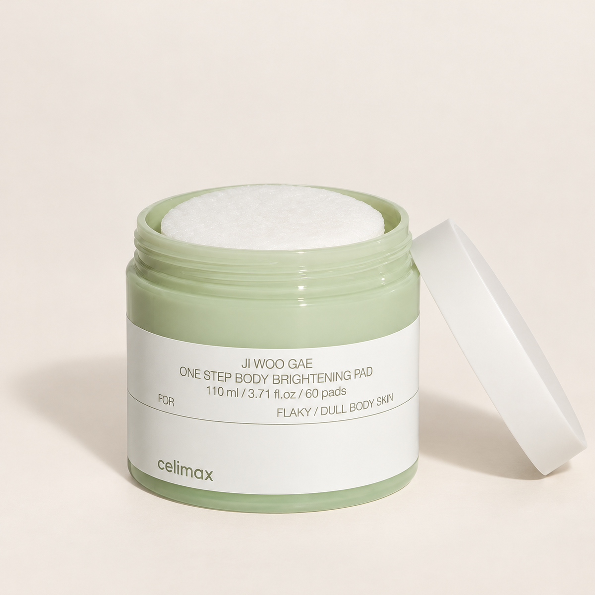 Celimax Ji Woo Gae One Step Body Brightening Pad open sage jar with 60 pads and white lid on a warm beige background