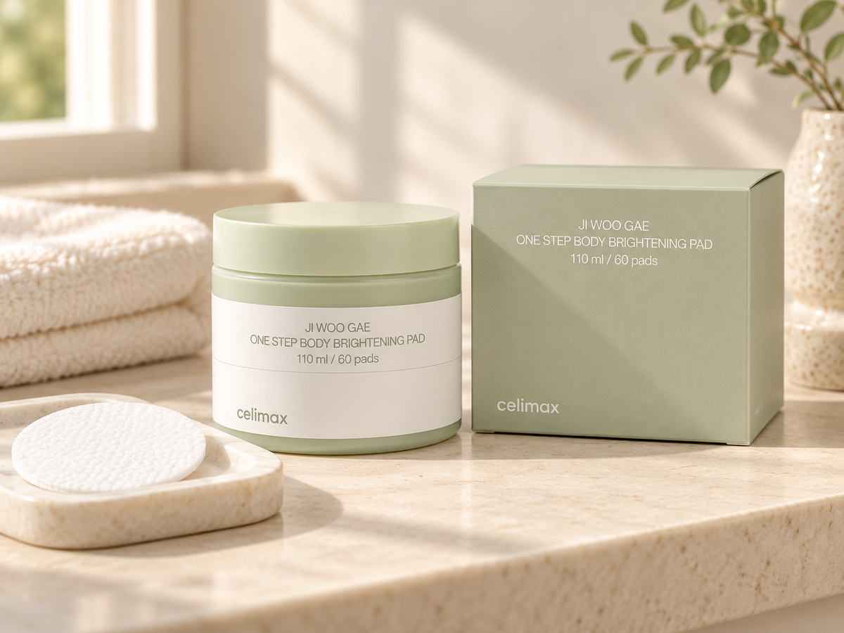 Celimax Ji Woo Gae body brightening pad jar and matching sage box with a white pad on an ivory bathroom ledge