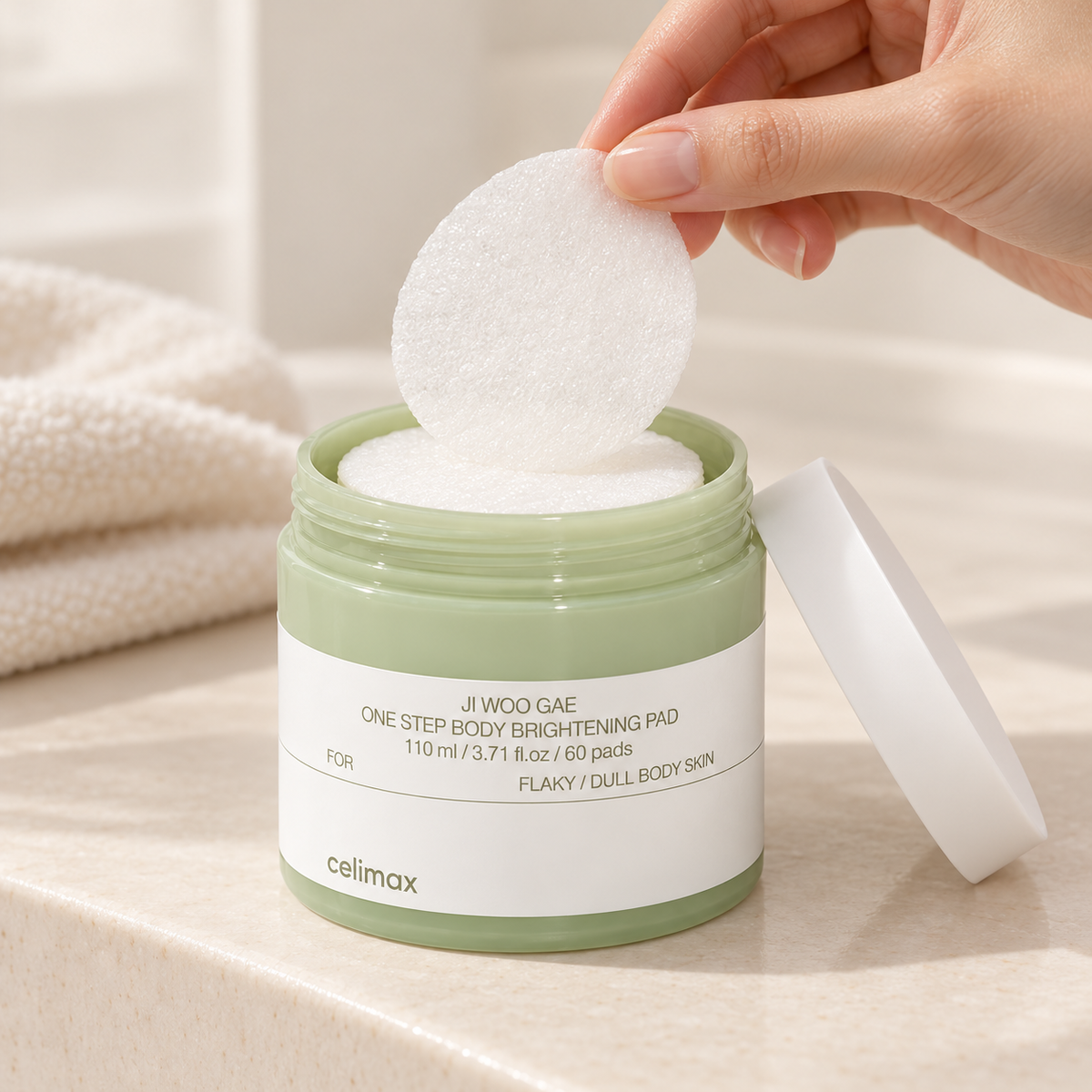Illustrative preparation: a hand lifts one pre-soaked pad from the open Celimax body-pad jar