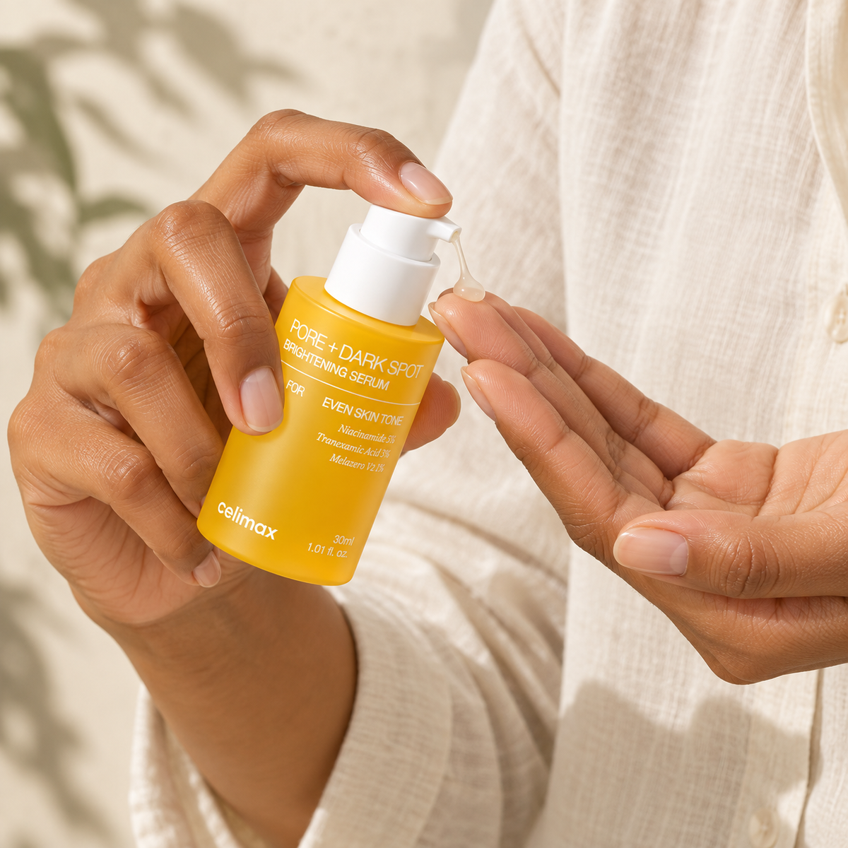 Hands dispensing Celimax Brightening Serum from the pump onto fingertips