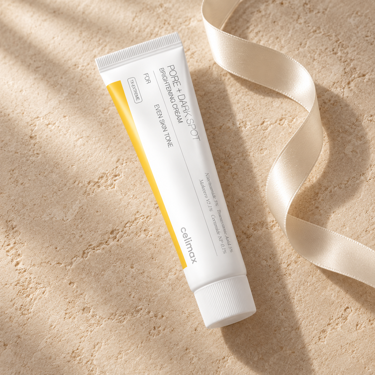 Celimax Pore + Dark Spot Brightening Cream tube on warm beige stone