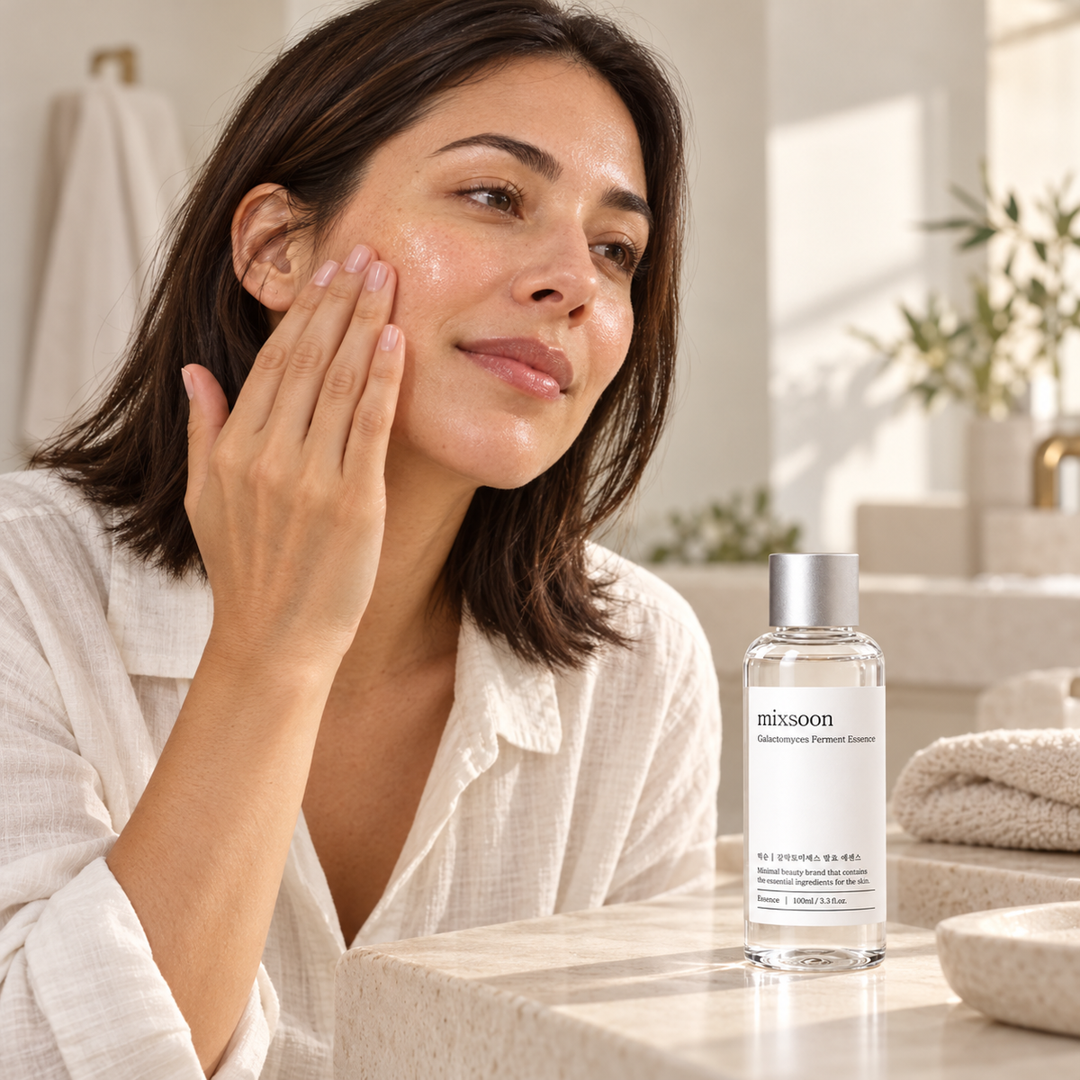 Woman gently patting essence onto her cheek beside a Mixsoon Galactomyces bottle